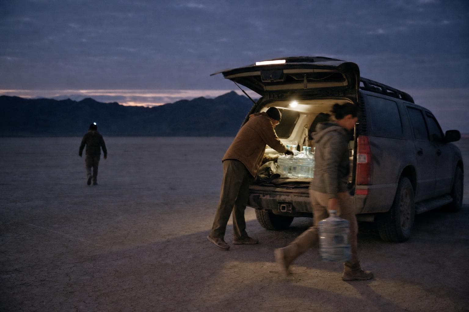 Friends unloading water and shade from a car on a dry lakebed